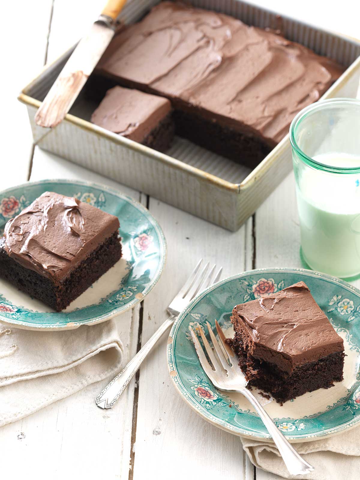 A chocolate cake pan cake topped with chocolate frosting and a slice on a plate