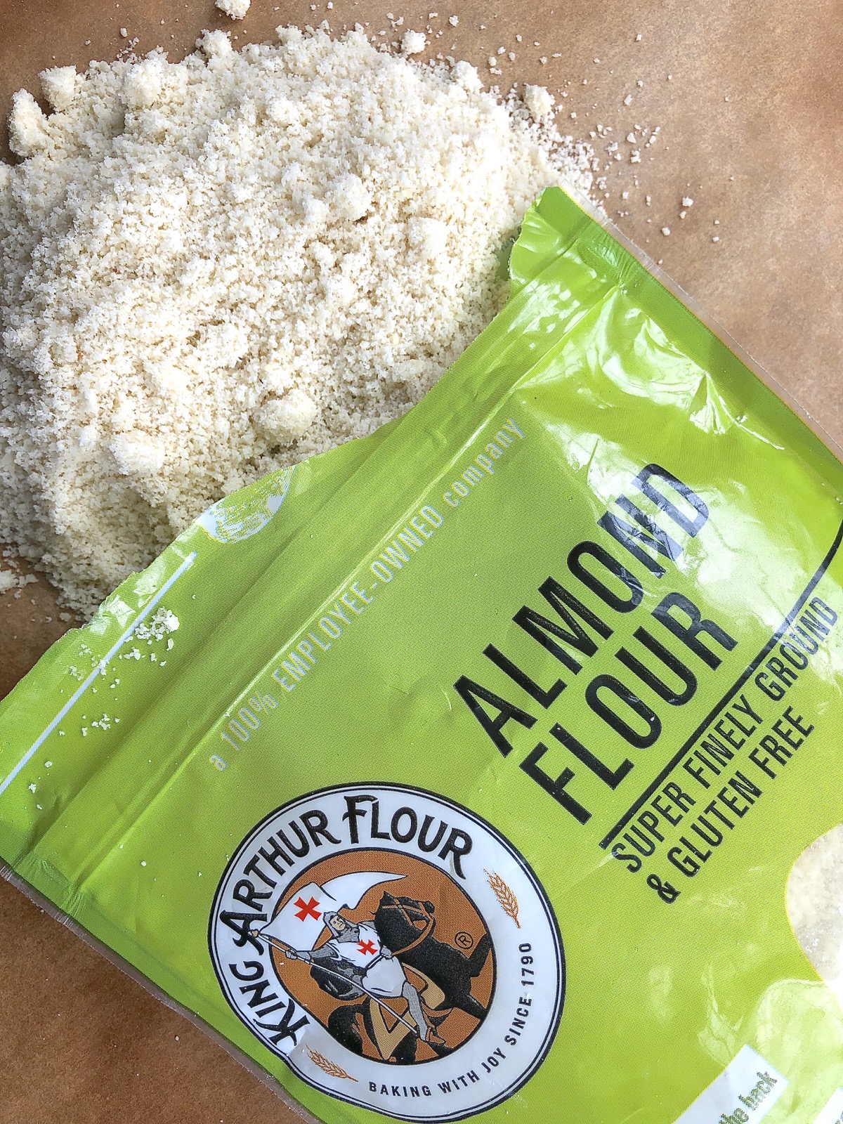 Open bag of almond flour with some spilled out on cutting board.