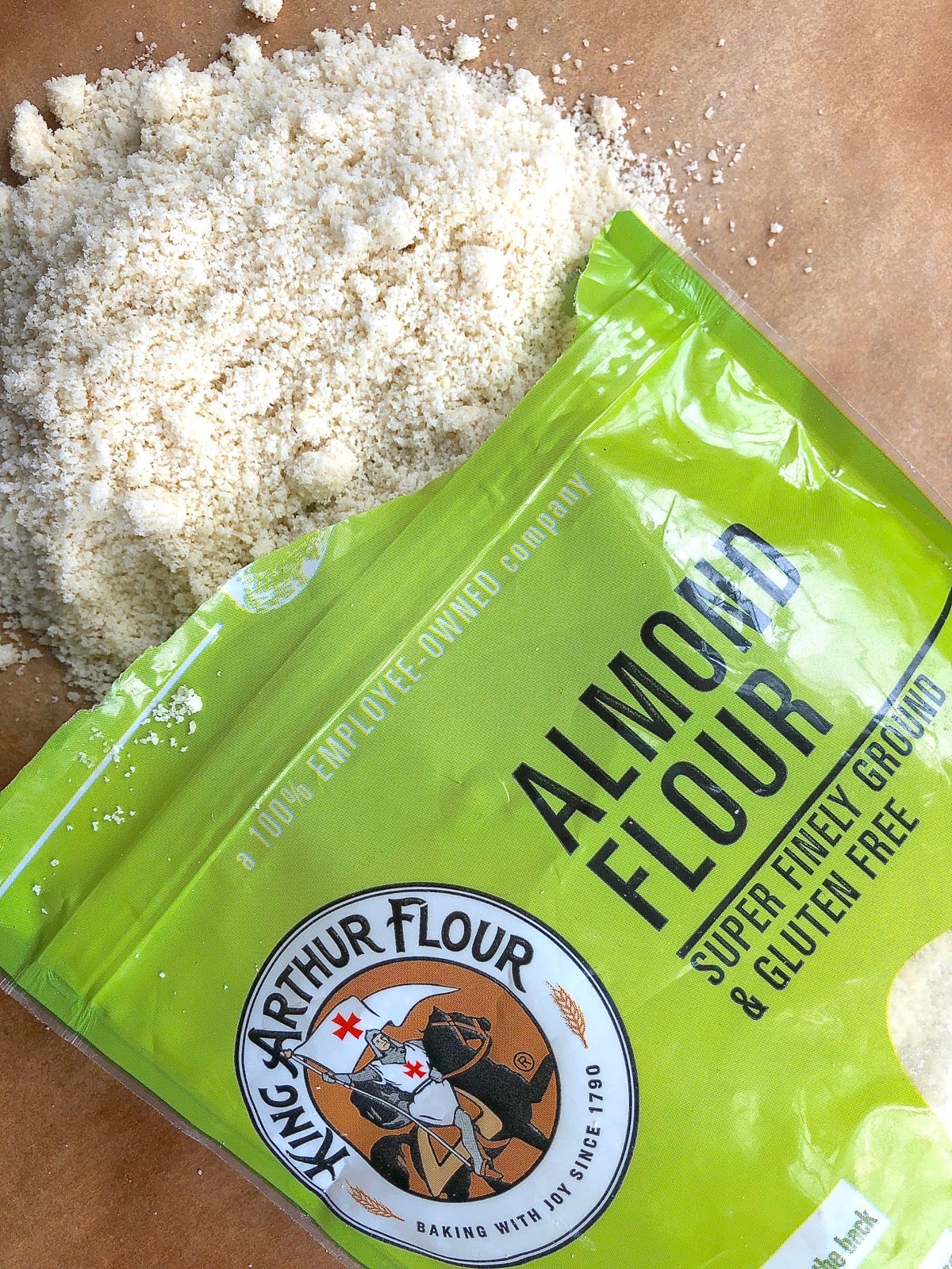 Open bag of almond flour with some spilled out on cutting board.