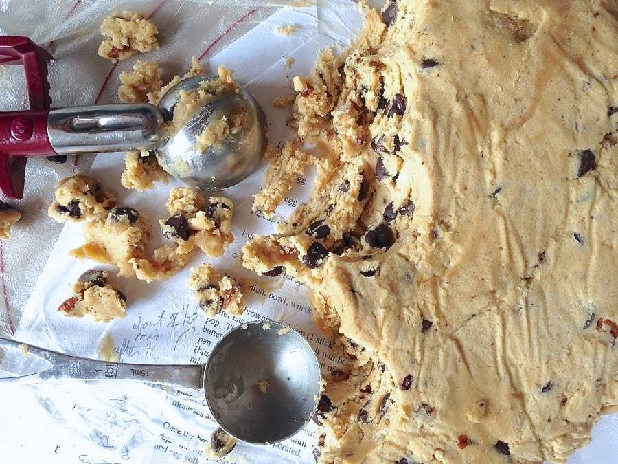 Chocolate chip cookie dough, measuring spoon, and cookie scoop, dough ready to be scooped.