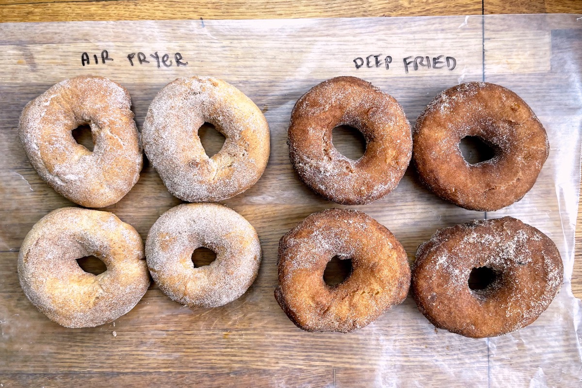 Four deep-fried doughnuts and four air-fried doughnuts side by side on a piece of paper, showing their difference in color.