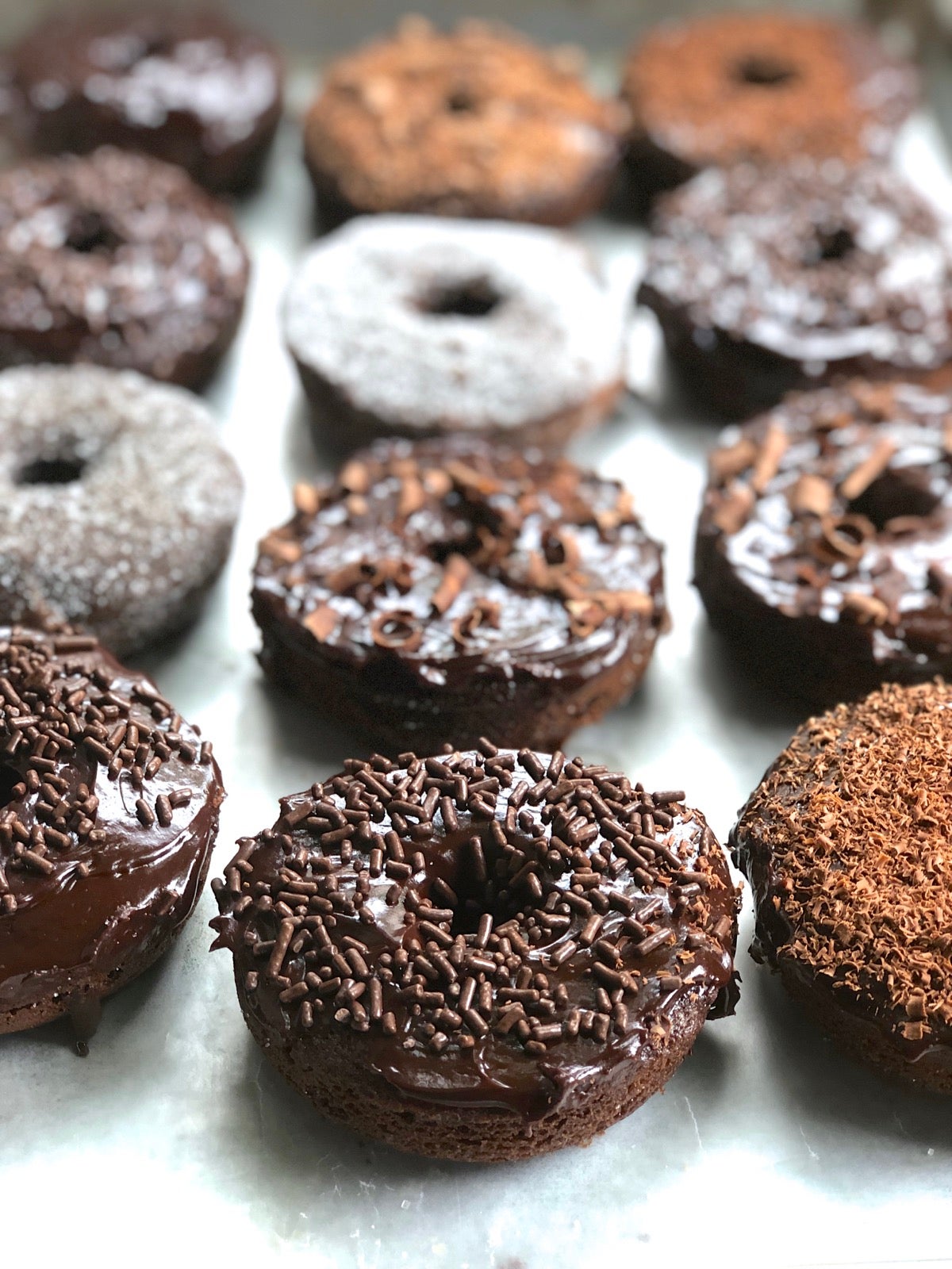 Iced Chocolate Fudge Cake Doughnuts on a cooling rack.