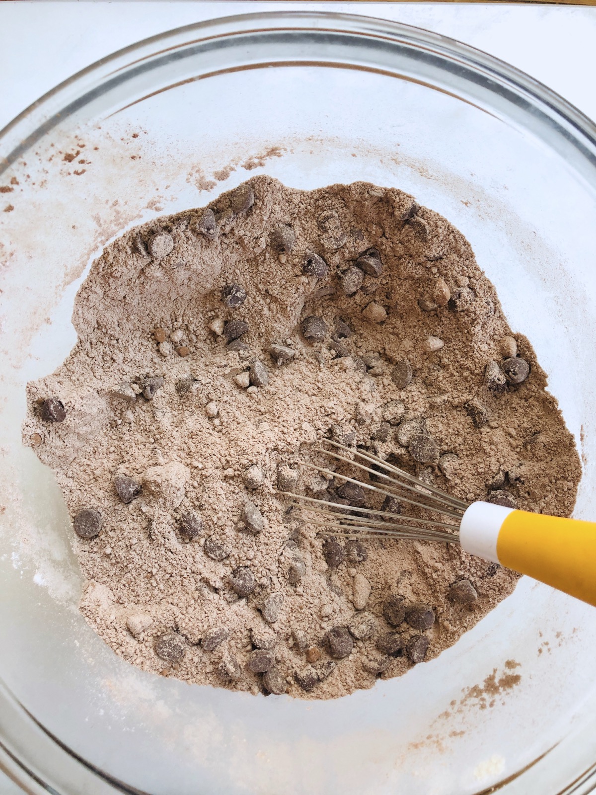 Dry ingredients for chocolate doughnuts whisked together in a mixing bowl.