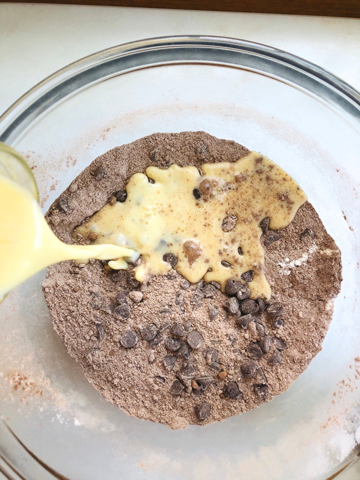 Eggs and milk being added to dry chocolate doughnut ingredients.