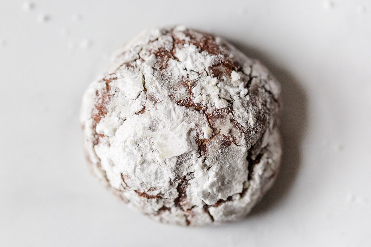 A close-up shot of a Chocolate Crinkle on a marble surface showing the cracks in the sugar coating