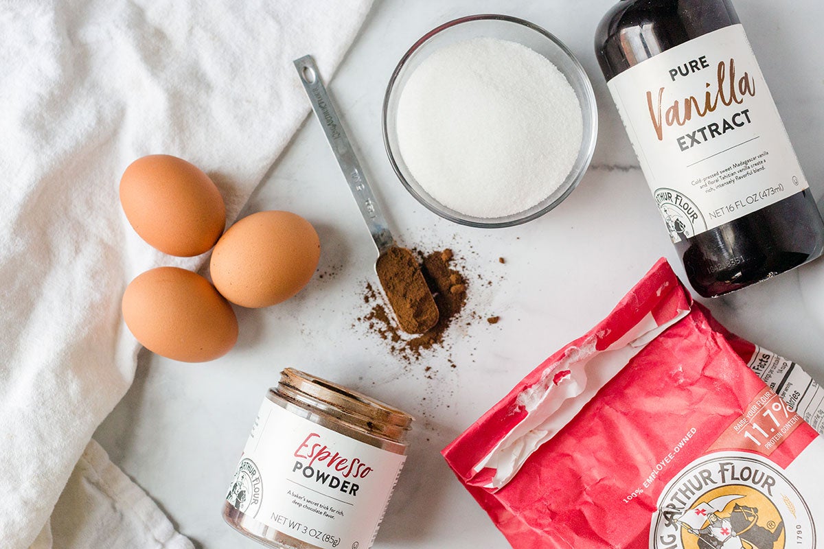 Ingredients to make chocolate crinkles, including King Arthur Flour, eggs, sugar, vanilla, and espresso powder