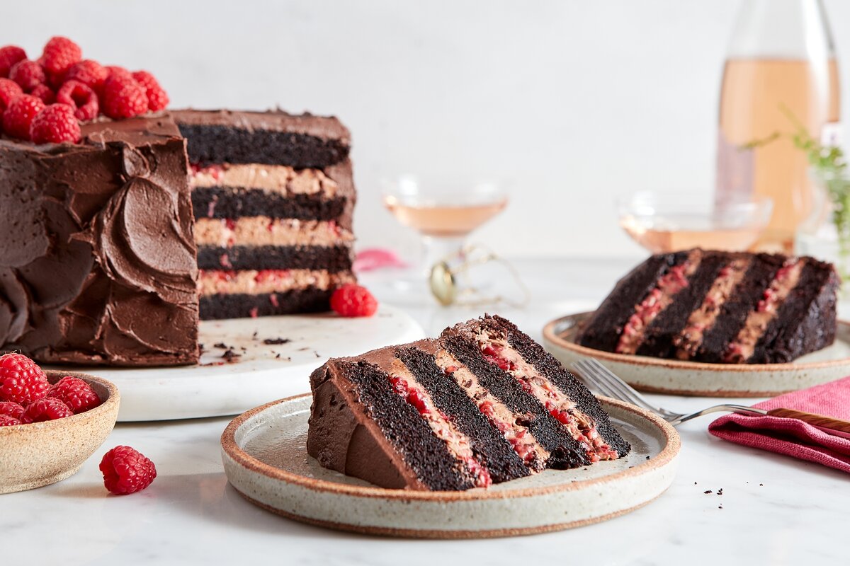 A chocolate cake with a few slices removed, showing off layers of chocolate mousse and raspberries inside