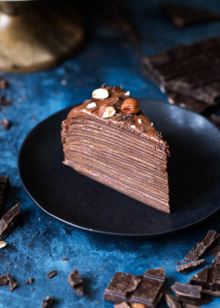 A tall slice of chocolate crepe cake on a plate
