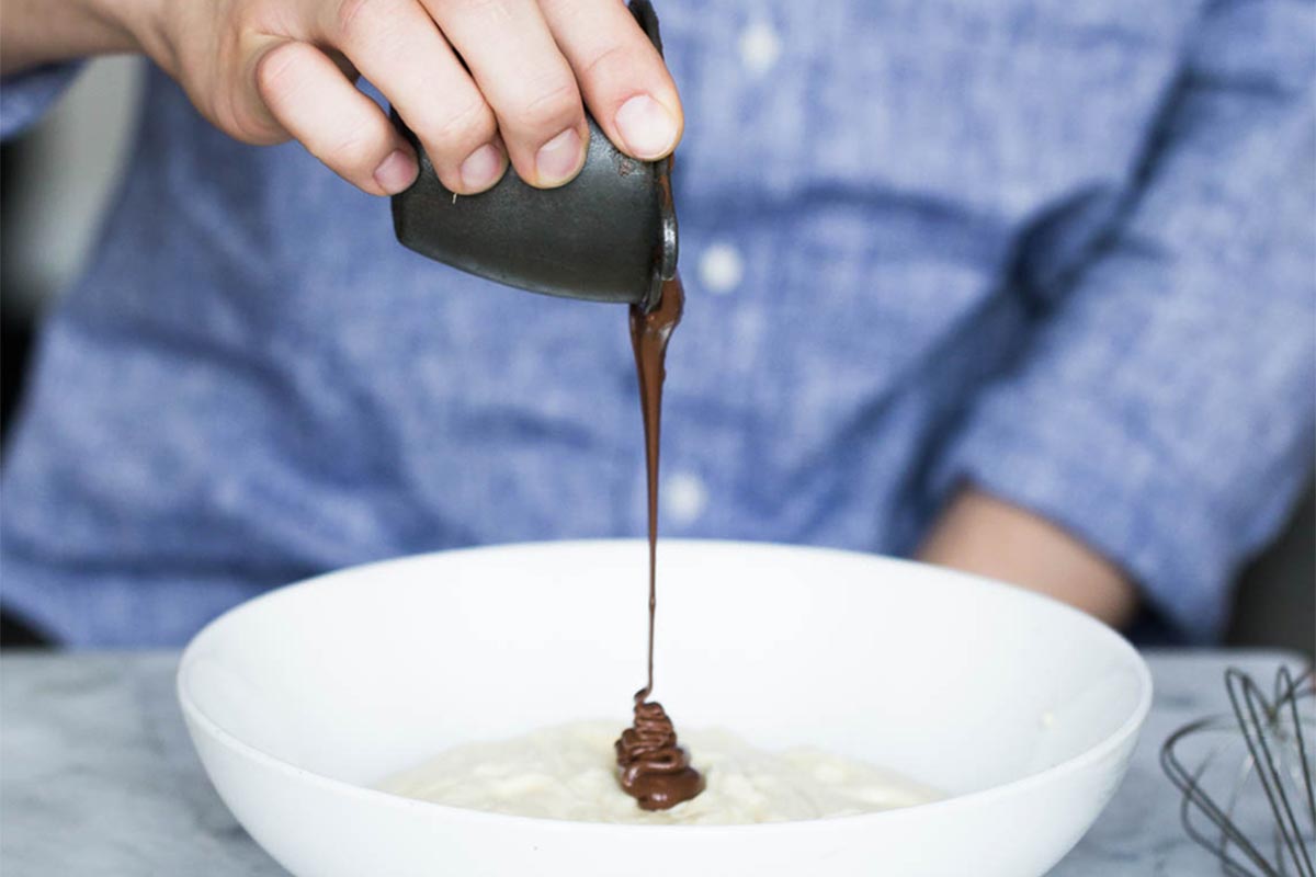 A baker adding chocolate hazelnut spread to pastry cream