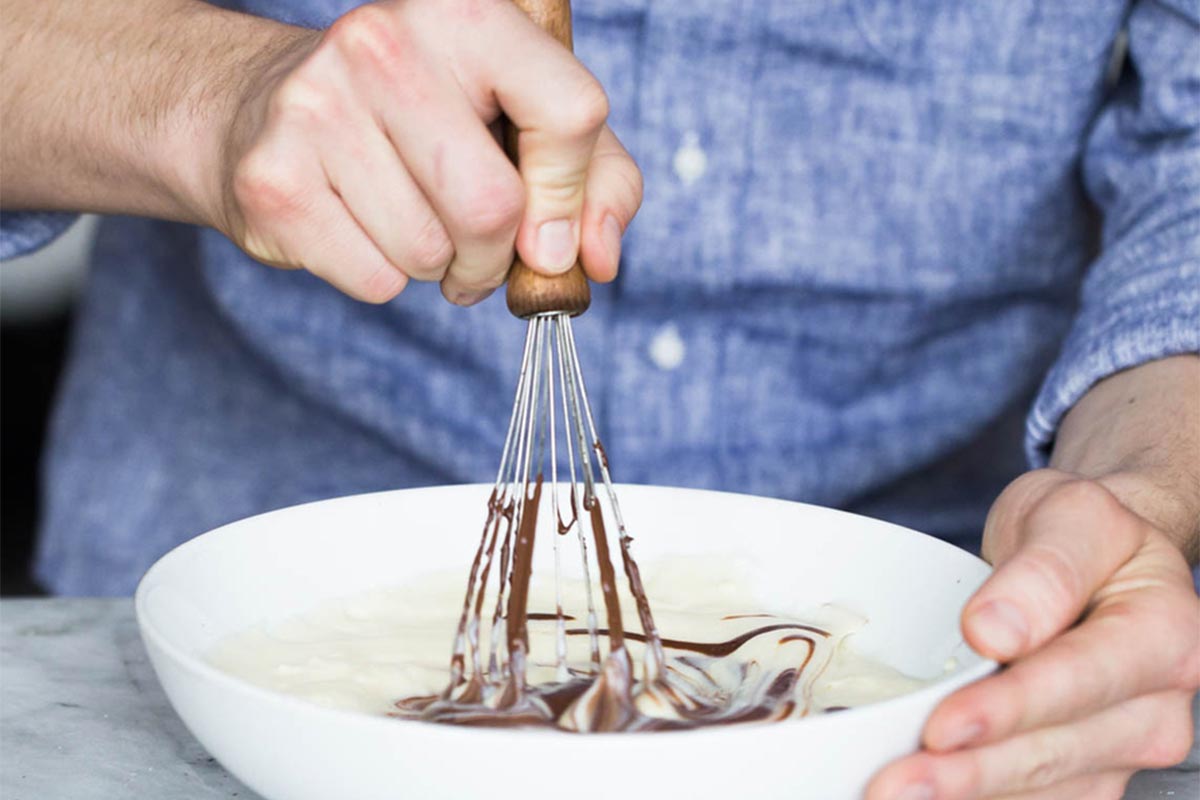 A baker whisking chocolate pastry cream