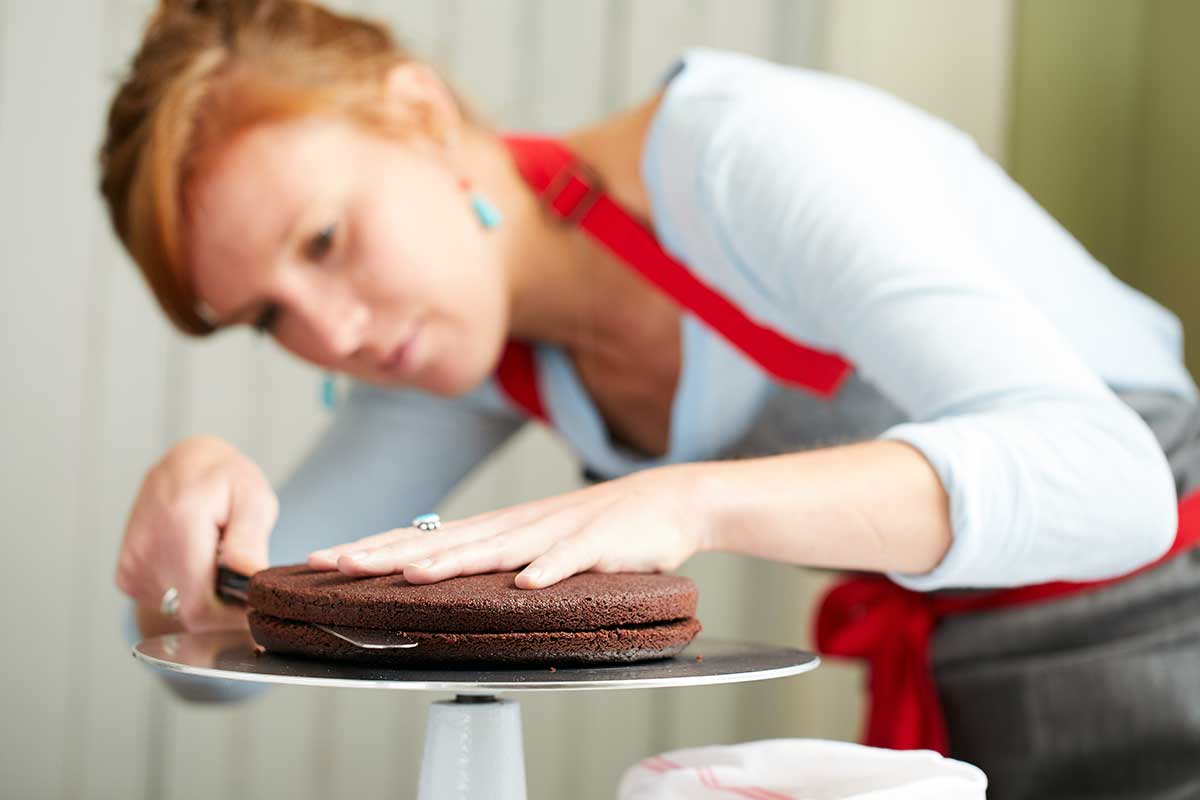 A baker splitting a layer cake into two pieces