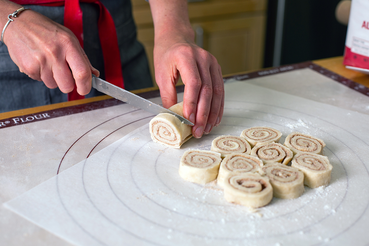 A baker slicing cinnamon bun pie crust into rounds
