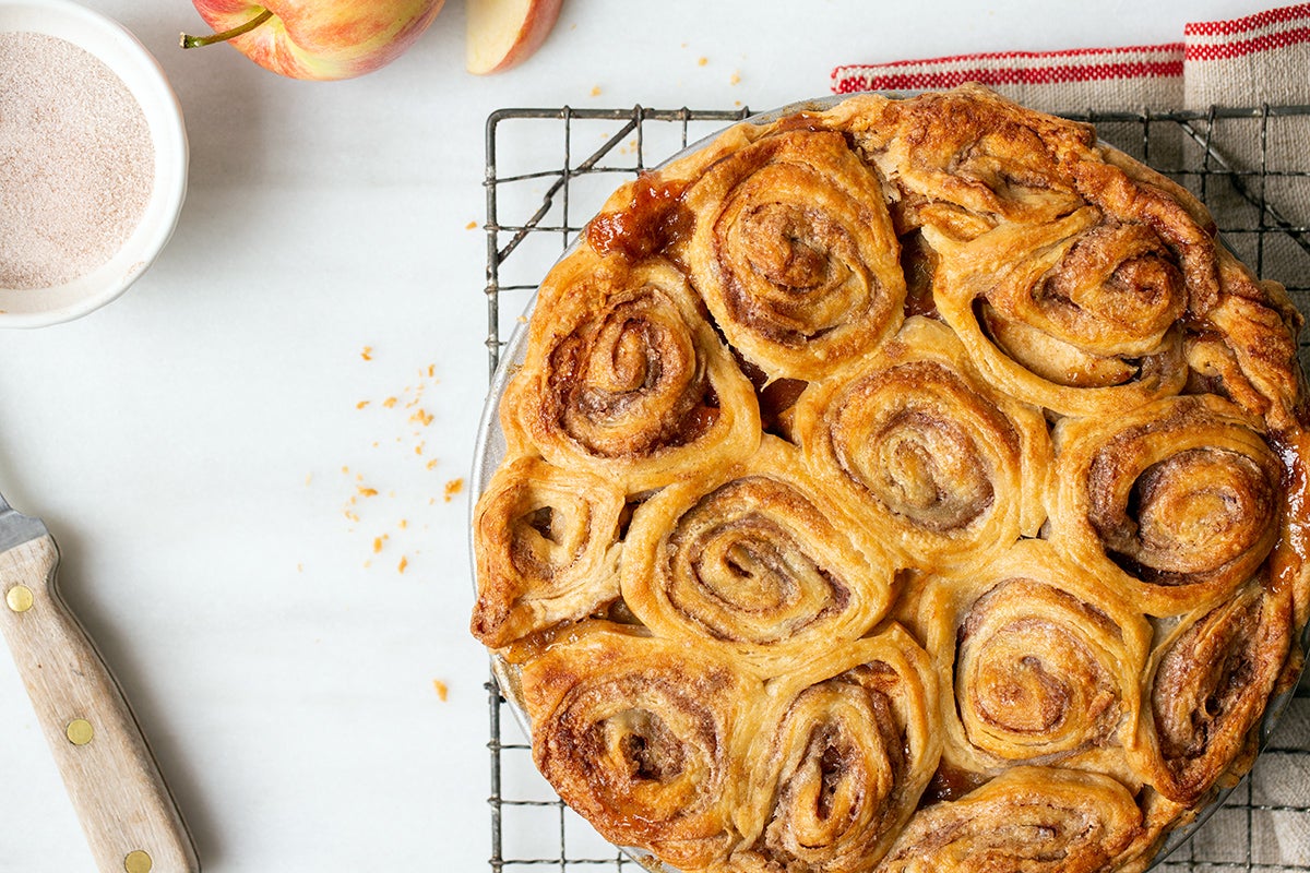 Apple pie with a cinnamon bun crust on a cooling rack, fresh from the oven