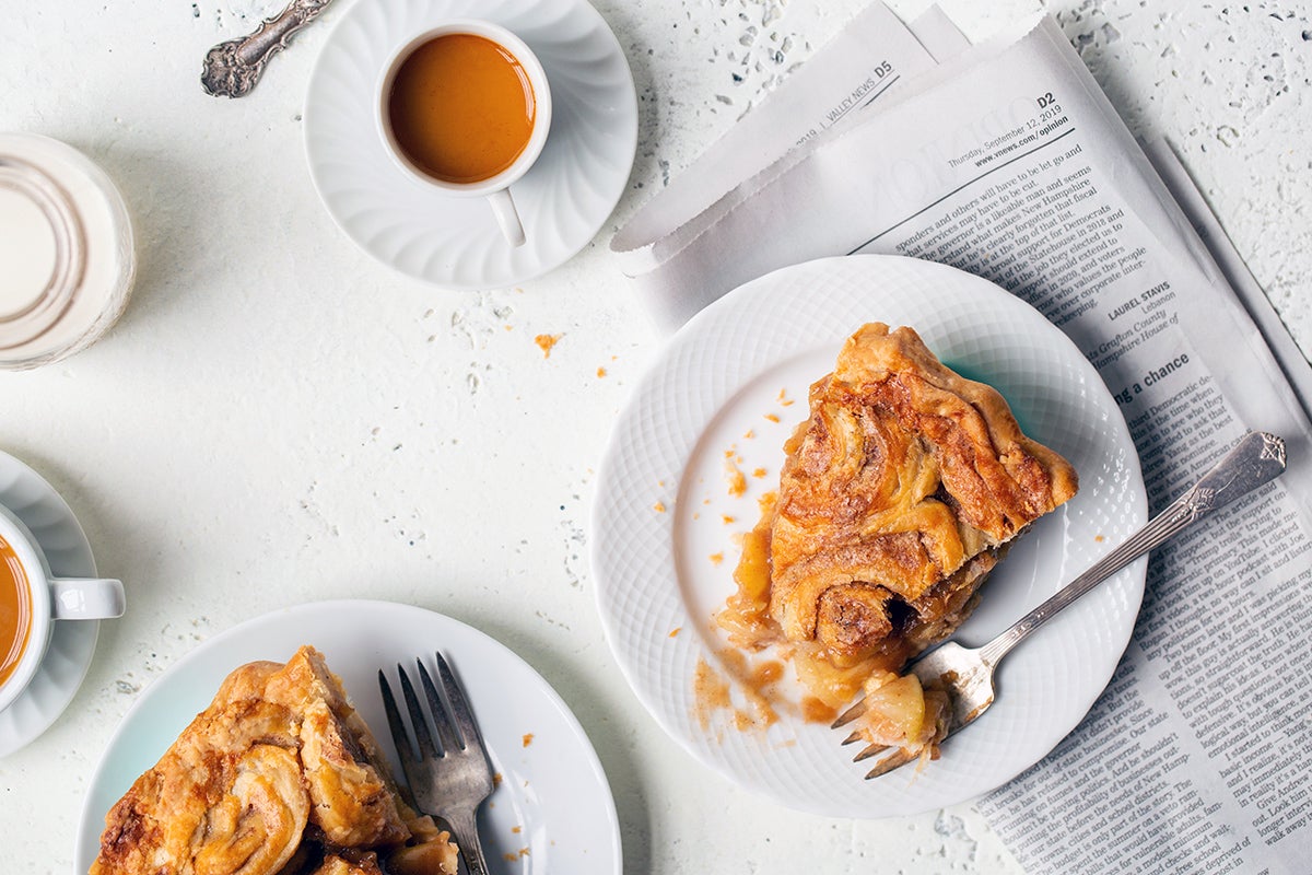 Slices of cinnamon bun apple pie on plates with espresso