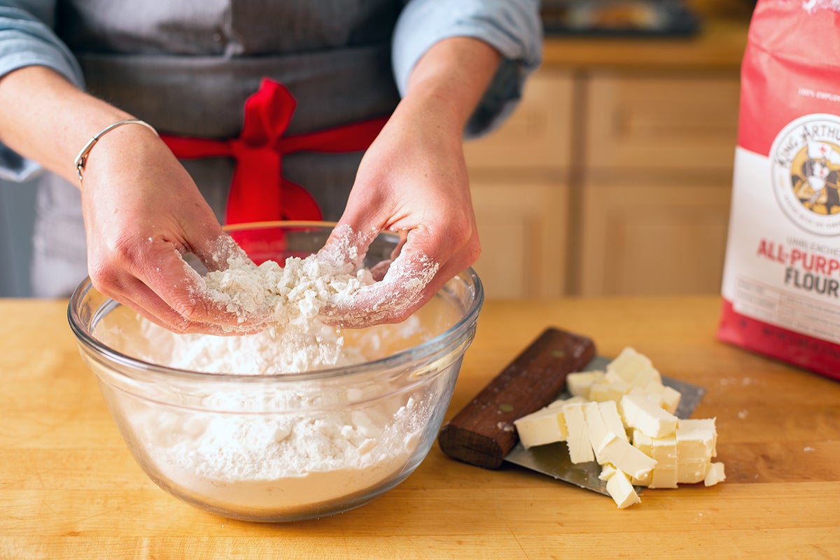 A baker working butter into flour to make pie dough