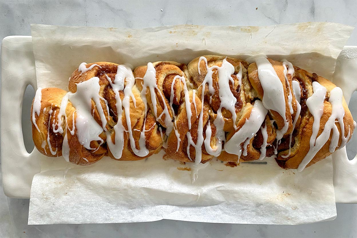 A loaf of cinnamon roll bread drizzled with glaze