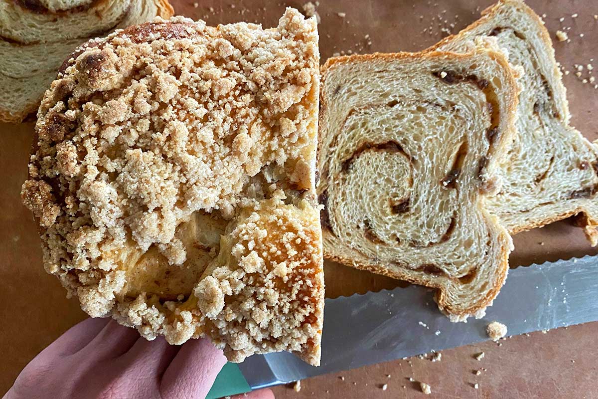 A baker slicing into a loaf of cinnamon swirl bread