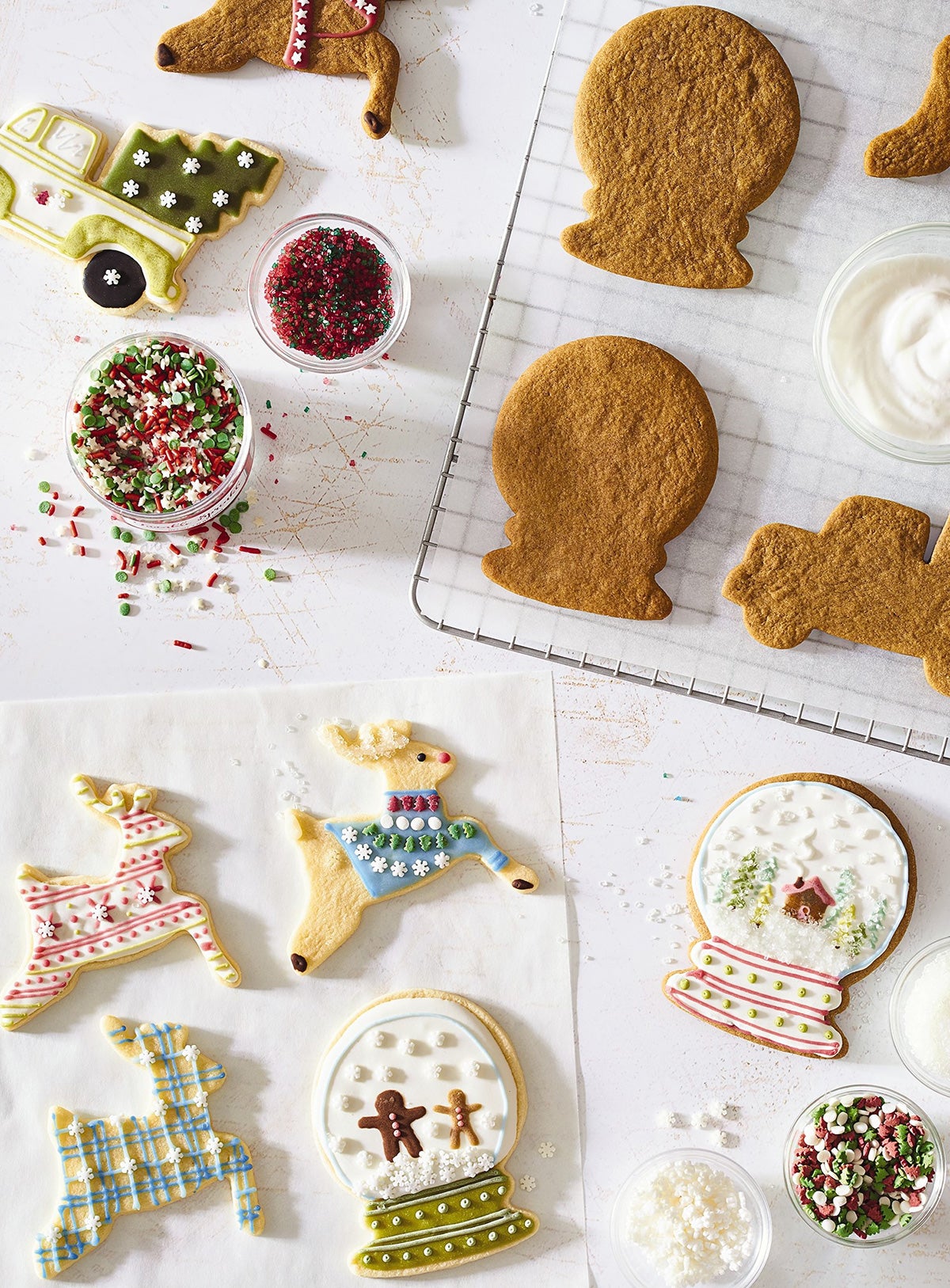 Christmas cookies decorated with naturally-colored icing on a kitchen table with sprinkles