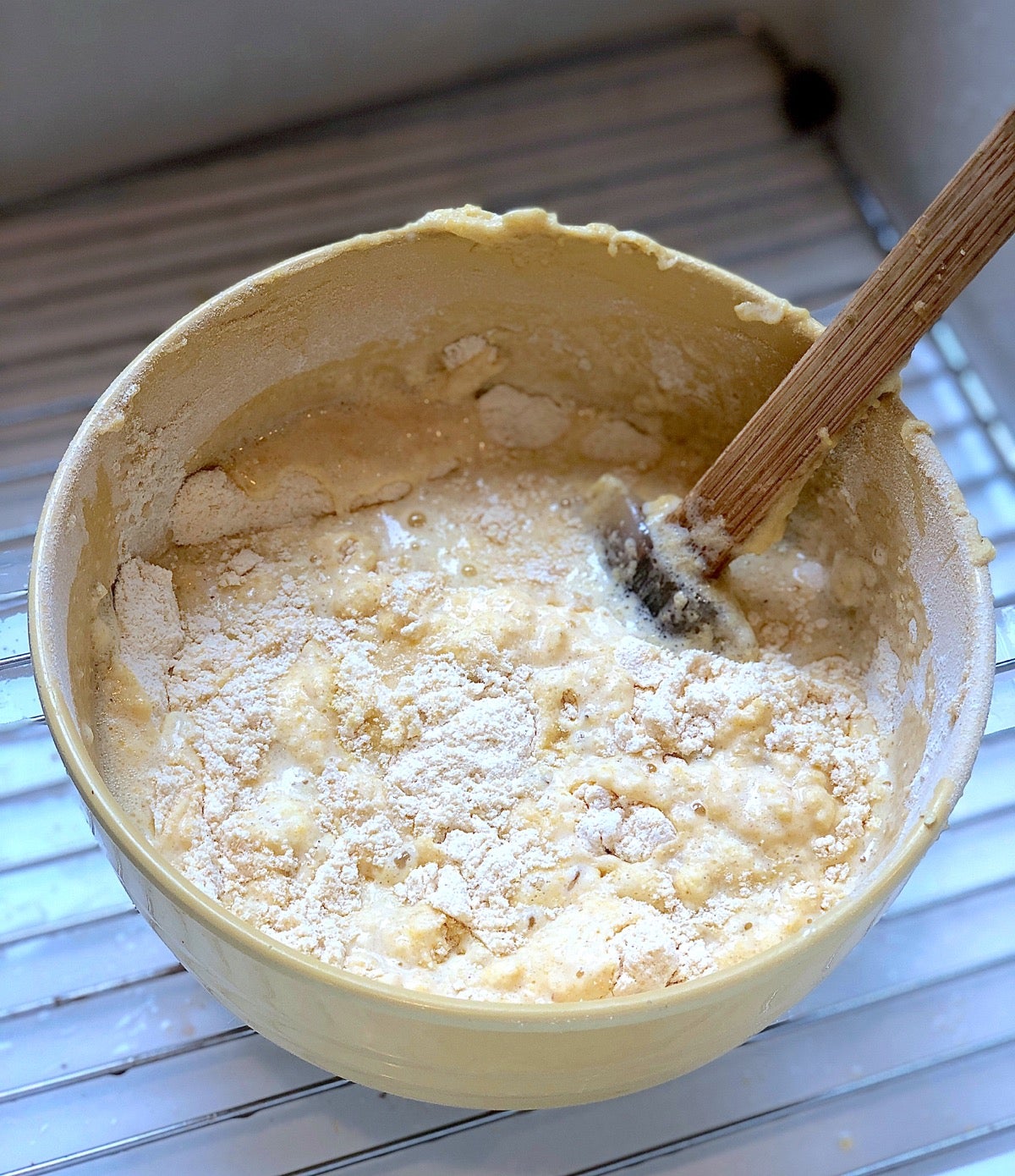 Cornbread ingredients being stirred in a bowl, the bowl placed in a sink to catch any spills