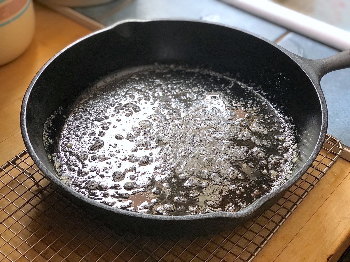 Cast iron skillet with melted butter, ready for cornbread batter