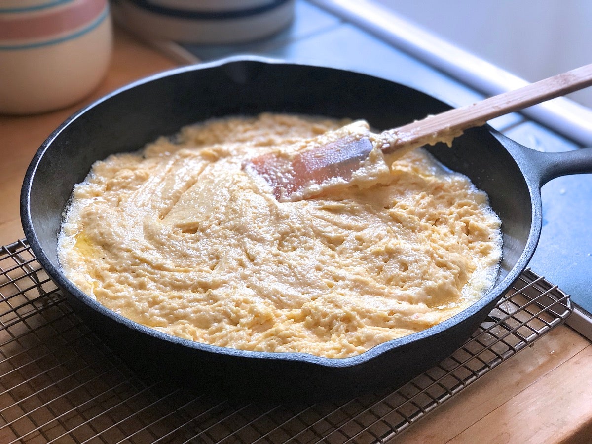 Cornbread batter spread in a 9" cast iron skillet, ready to bake