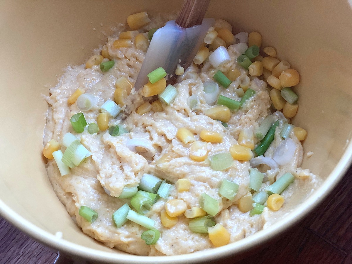 Stirring diced scallions and corn kernels into cornbread batter