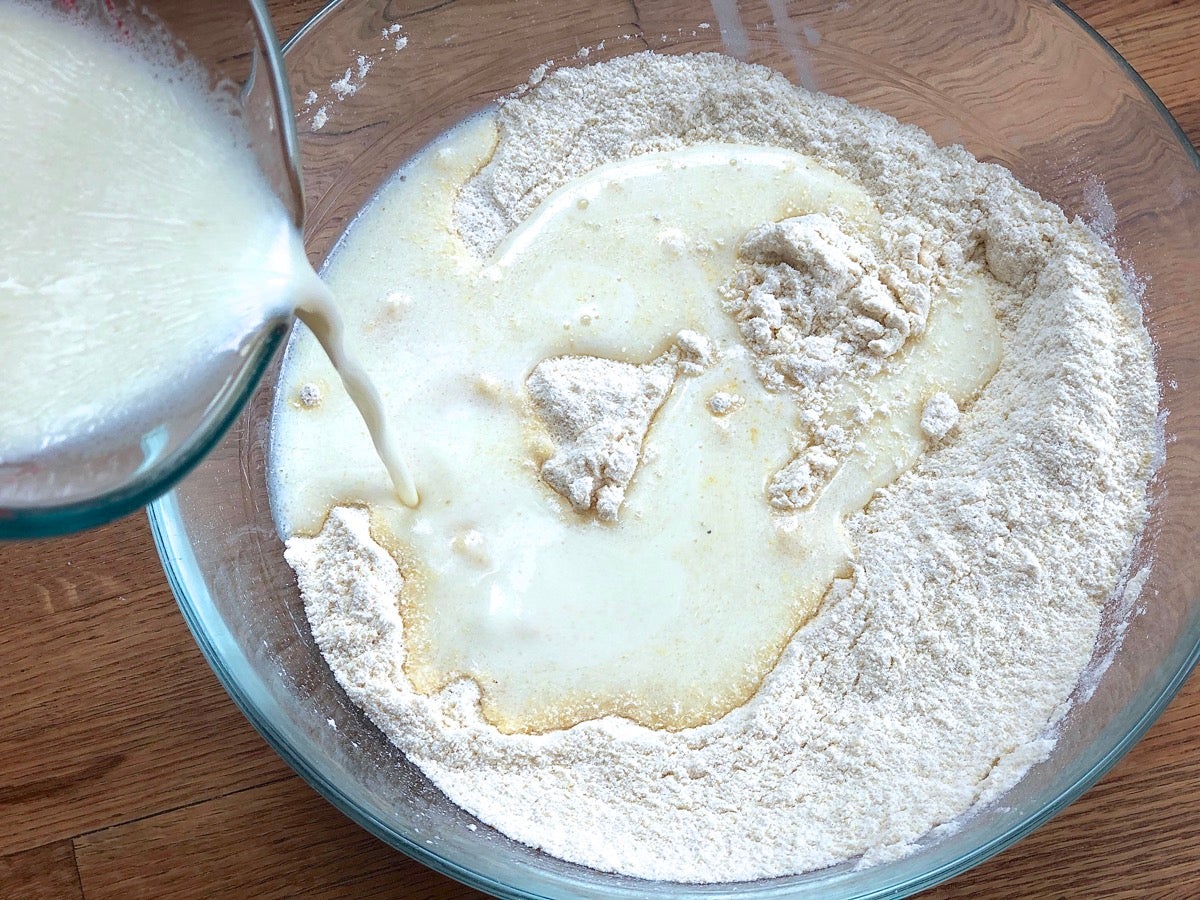 Pouring liquid ingredients into a bowl of dry ingredients to make cornbread