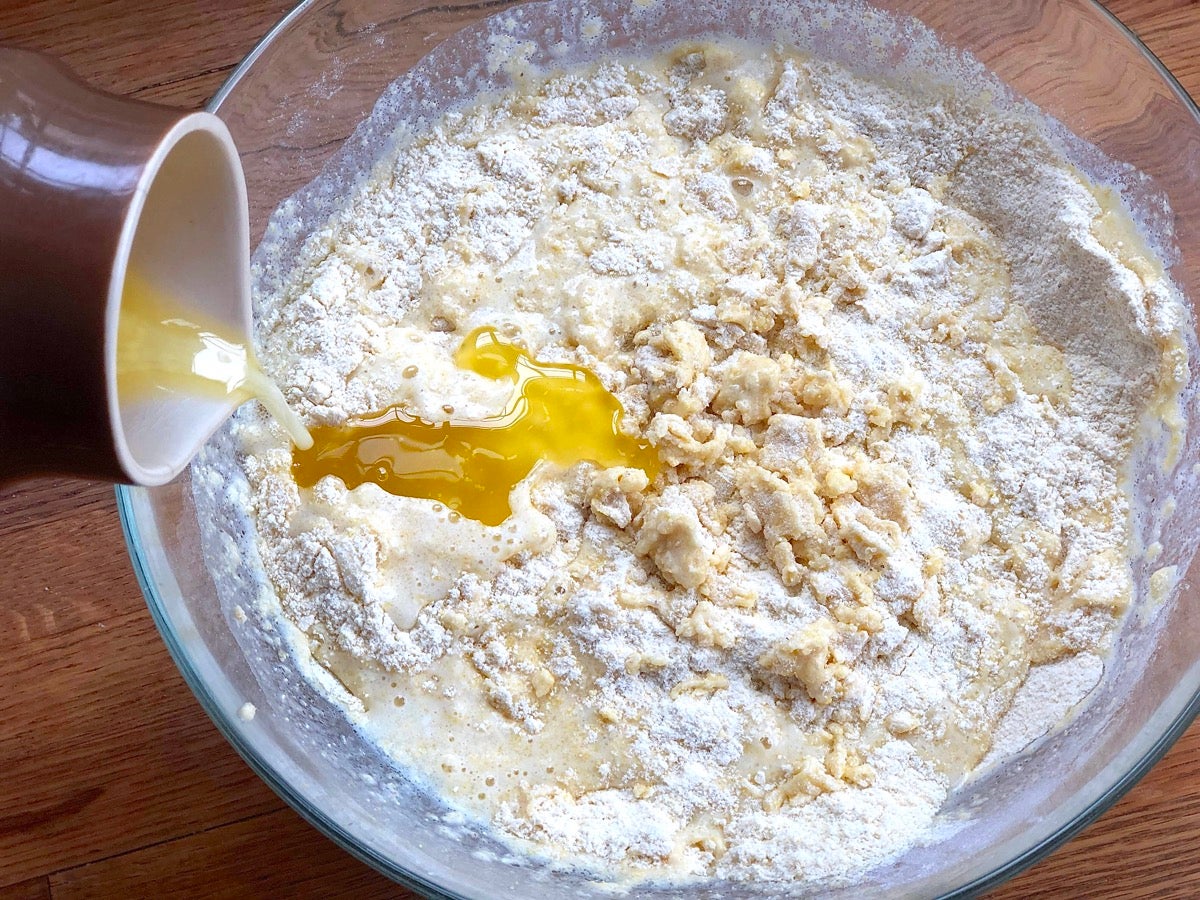 Pouring melted butter into a bowl of cornbread batter.