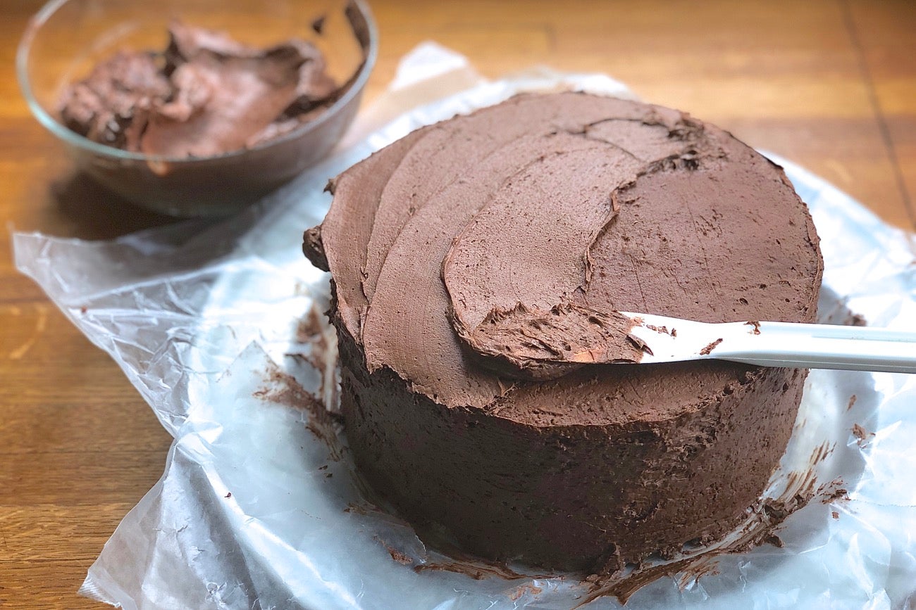 A double-layer yellow cake frosted with a chocolate crumb coat.