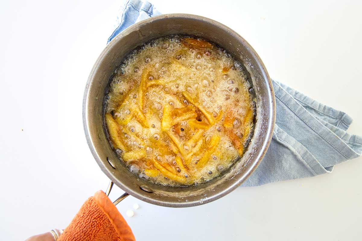 Saucepan with peels simmering in simple syrup of sugar and water