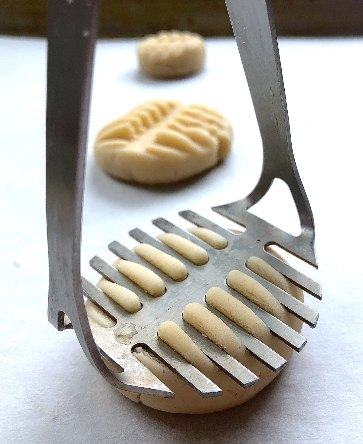 Using a potato masher to flatten a ball of shortbread cookie dough.