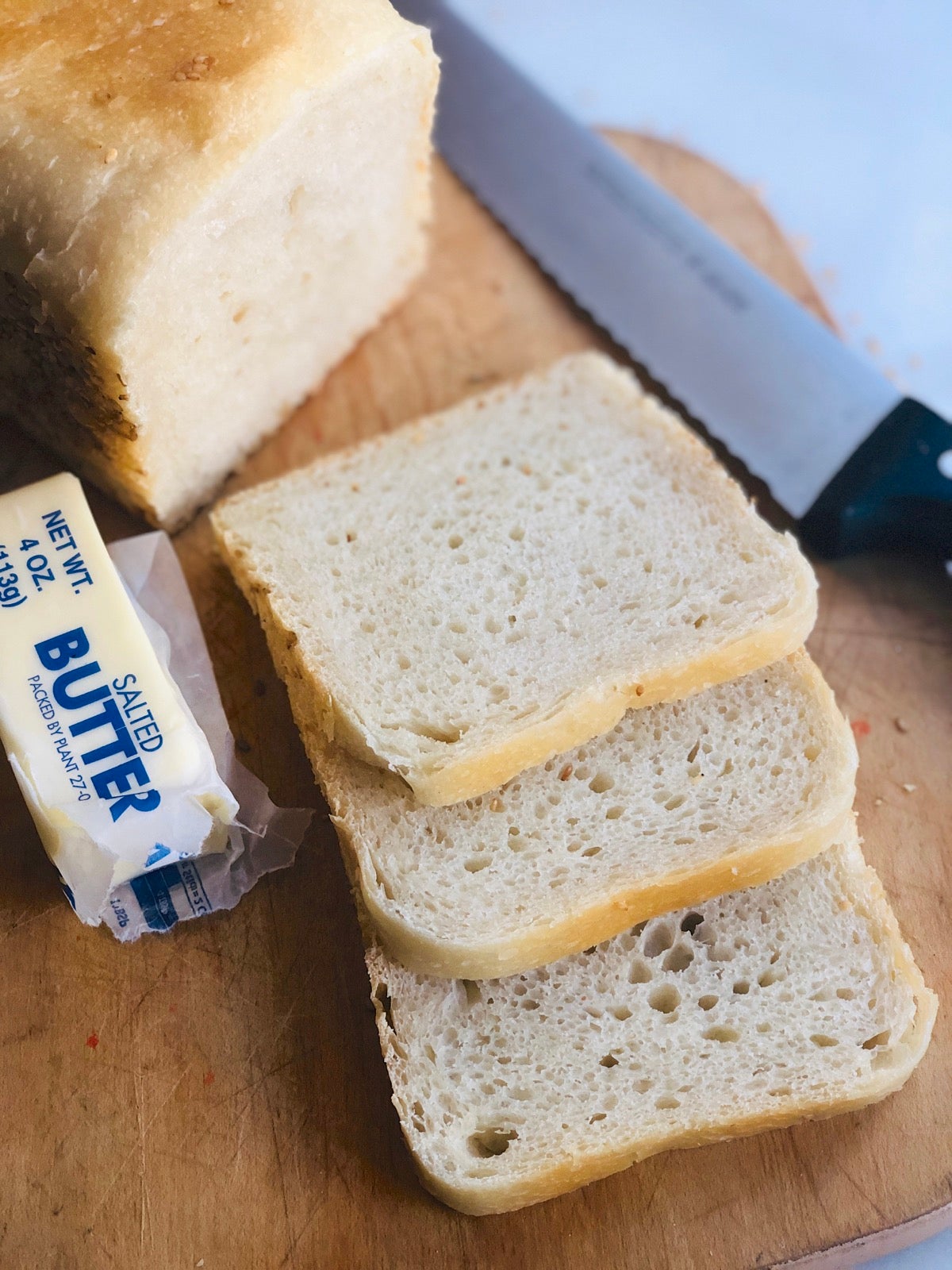 Sourdough sandwich bread made with 100% unbleached bread flour, sliced on a wooden cutting board.