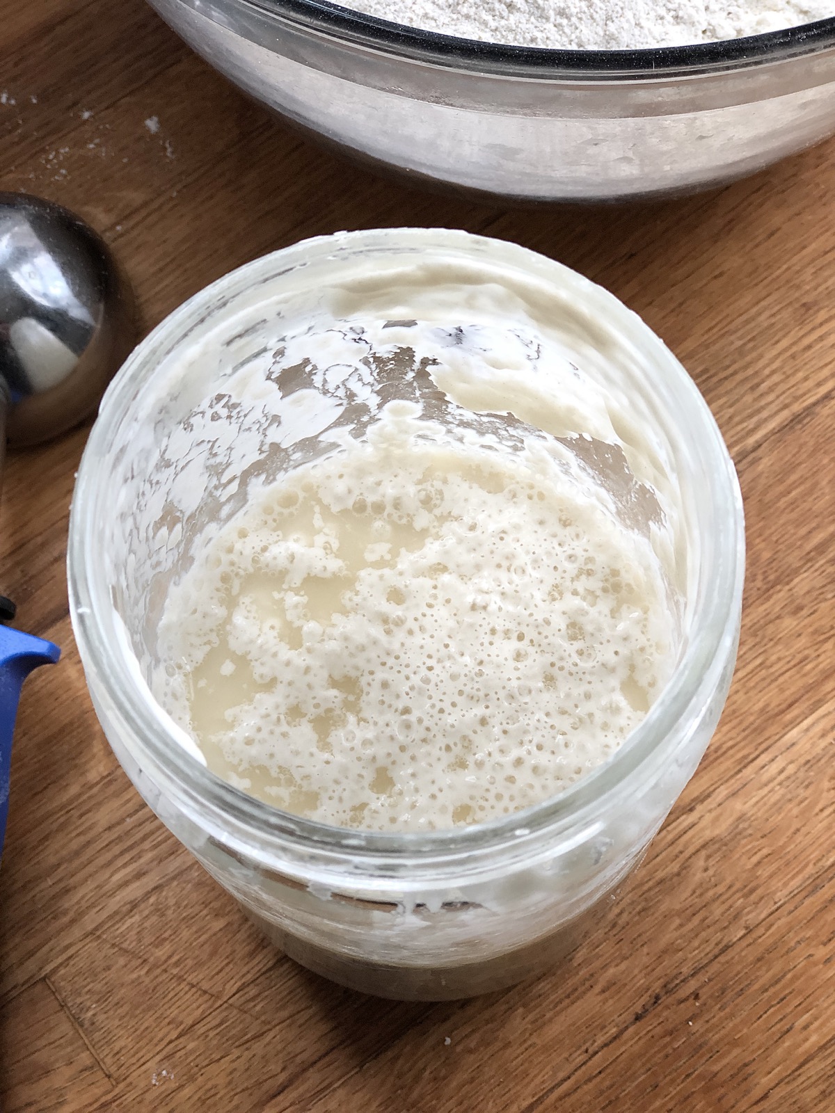 Sourdough starter in a jar, foam and liquid on top.