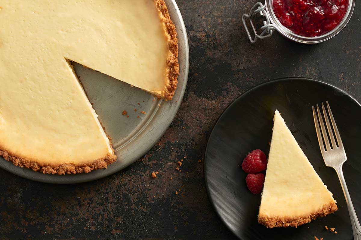 A cheesecake with a slice removed and placed on a plate