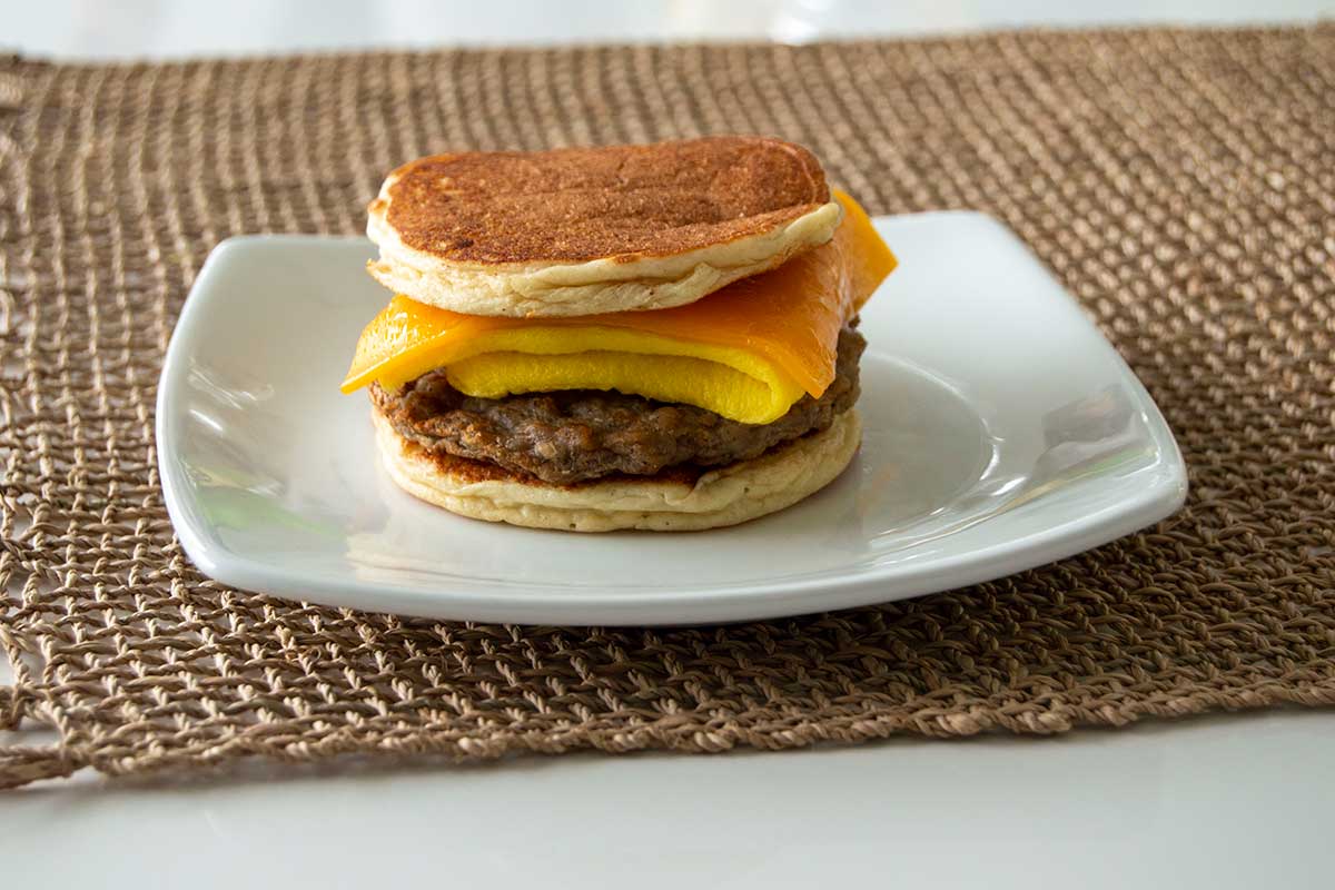 Plated egg and cheese breakfast sandwich, with pancakes as the bread