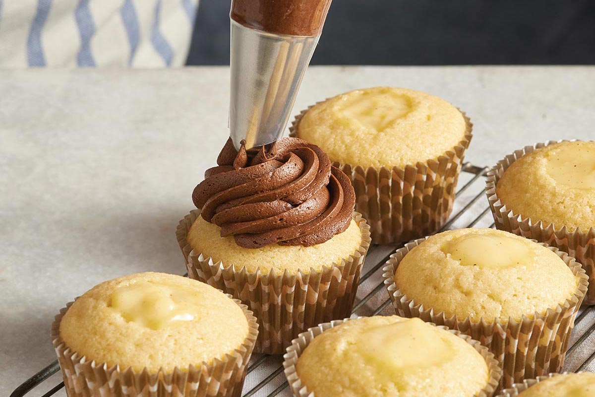 Yellow cupcakes being filled with chocolate cream
