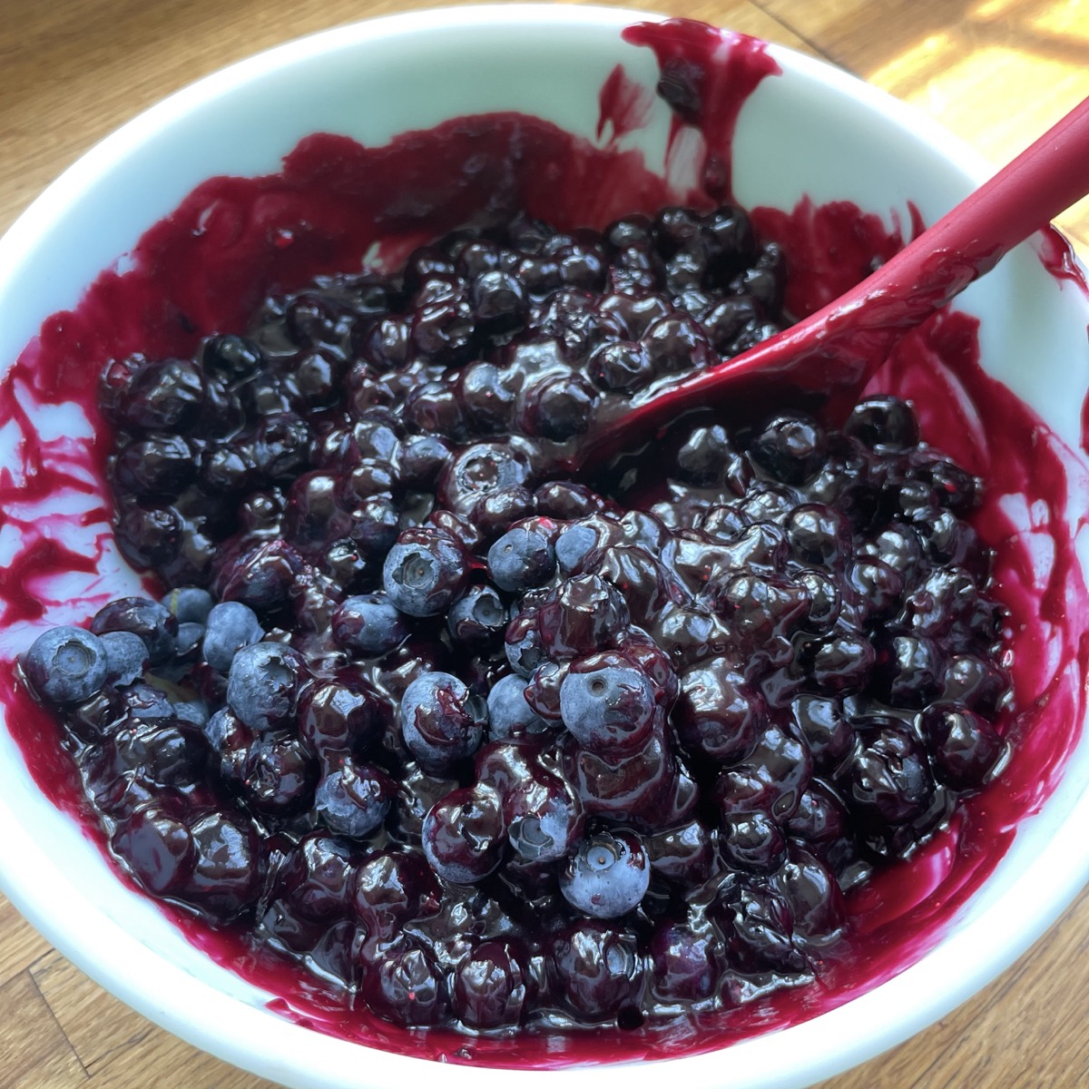 Fresh blueberries mixed with simmered berries and sugar in a bowl.