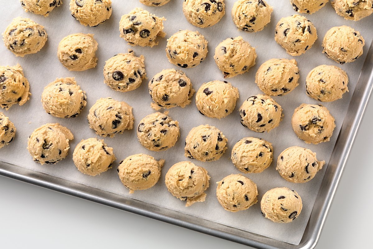 A half sheet pan covered in balls of cookie dough, ready to be frozen