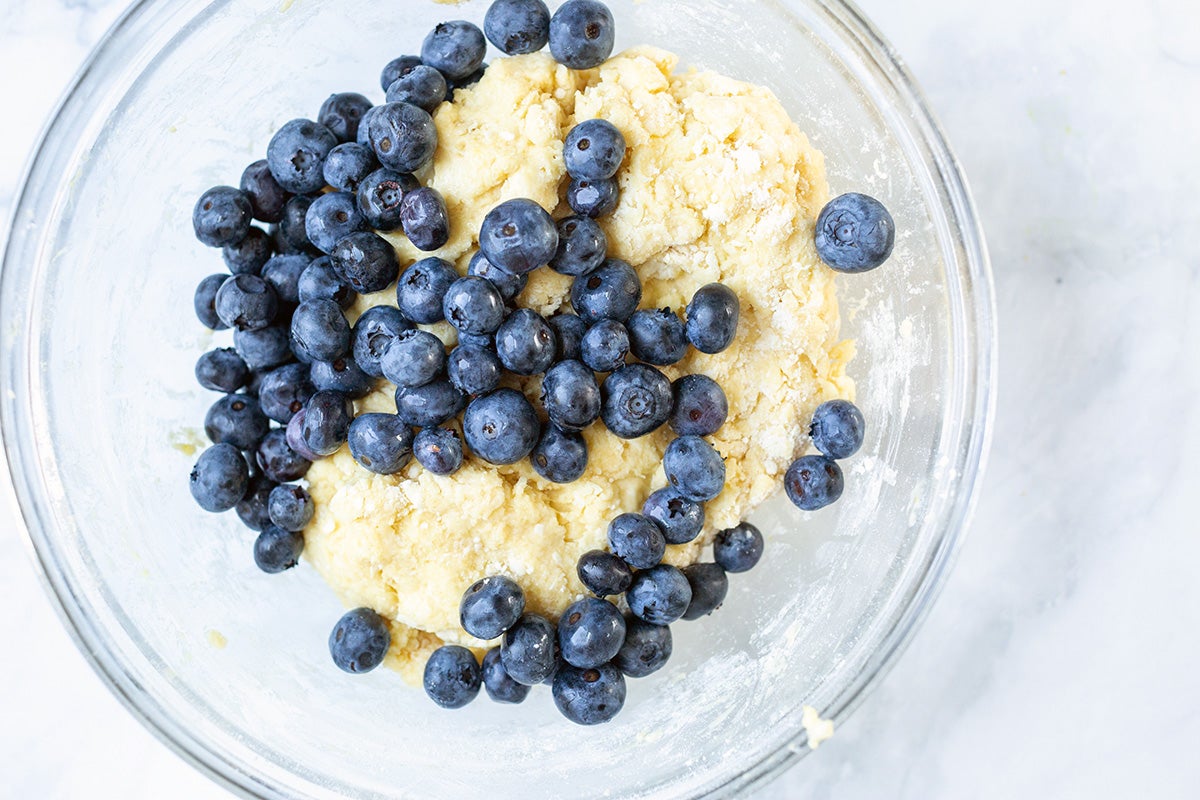 Unbaked dough scone in a mixing bowl with fresh blueberries on top, ready to be folded in