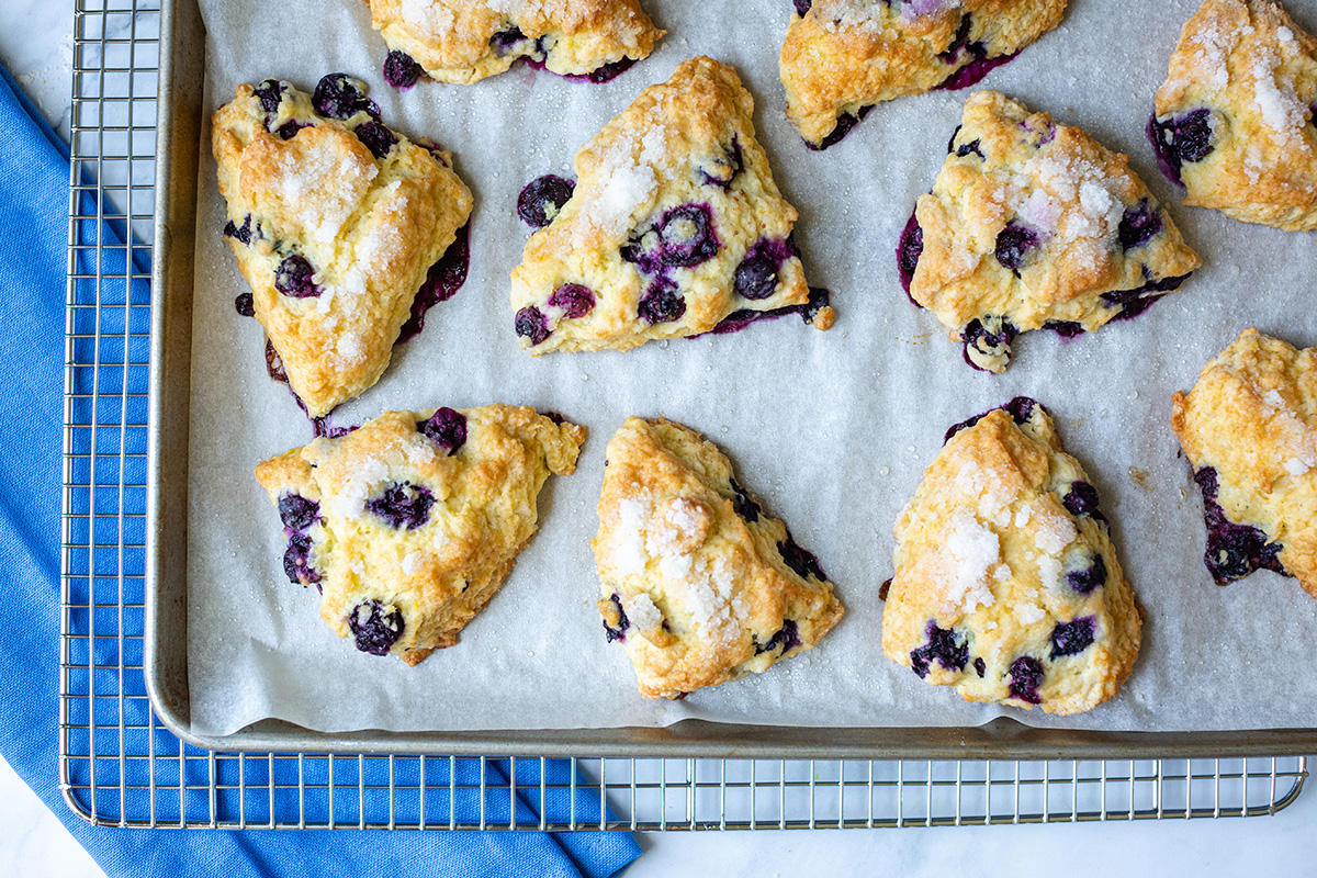 Fresh blueberry scones cooling on a rack with a blue linen