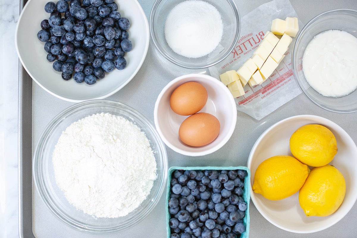 Small bowls of ingredients for Fresh Blueberry Scones on a tray including butter, sugar, flour, blueberries, and lemons