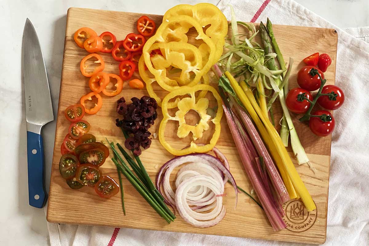 An assortment of fresh vegetables chopped and ready to go on top of a garden focaccia