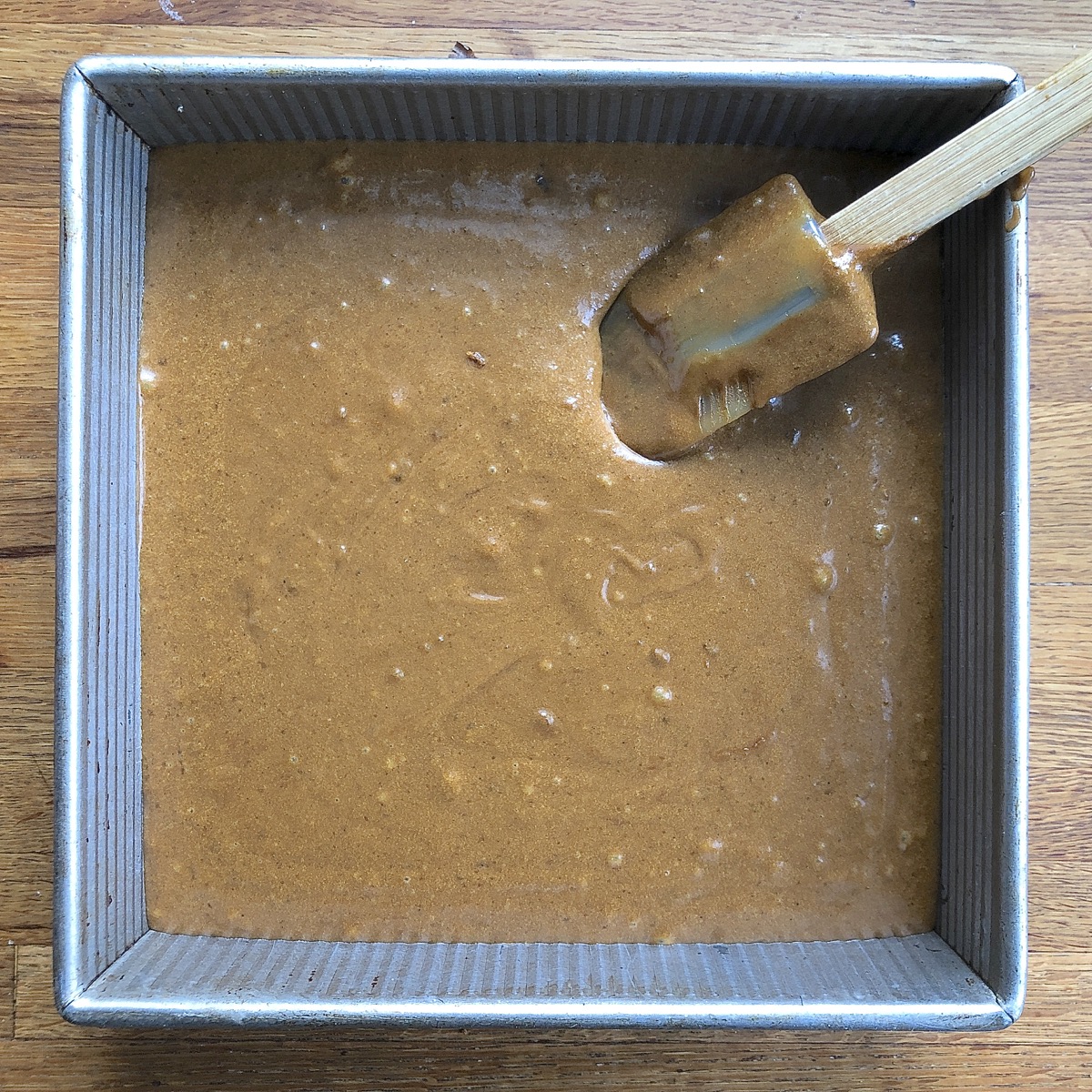 Gingerbread batter poured into a 9" square pan, ready to bake.