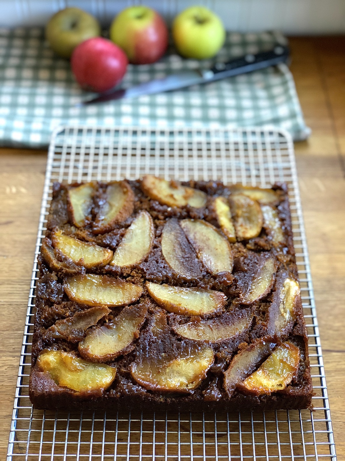 Apple upside-down gingerbread cake cooling in a pan on a rack.