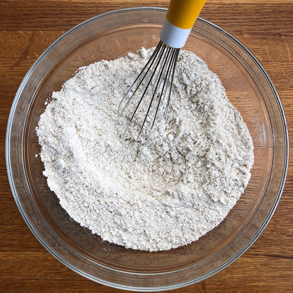 Dry ingredients for gingerbread cake whisked together in a glass bowl.