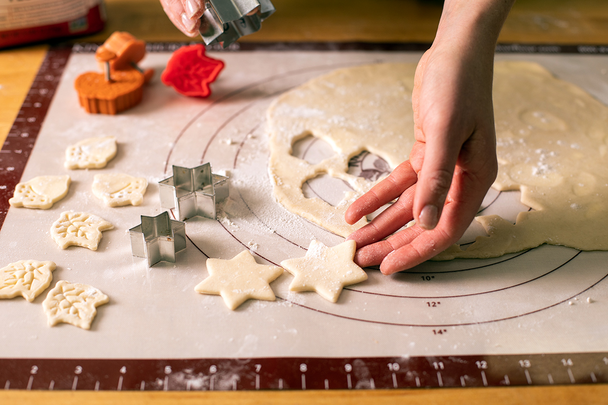 Pie dough rolled out on a silicone rolling mat with some shapes cut out