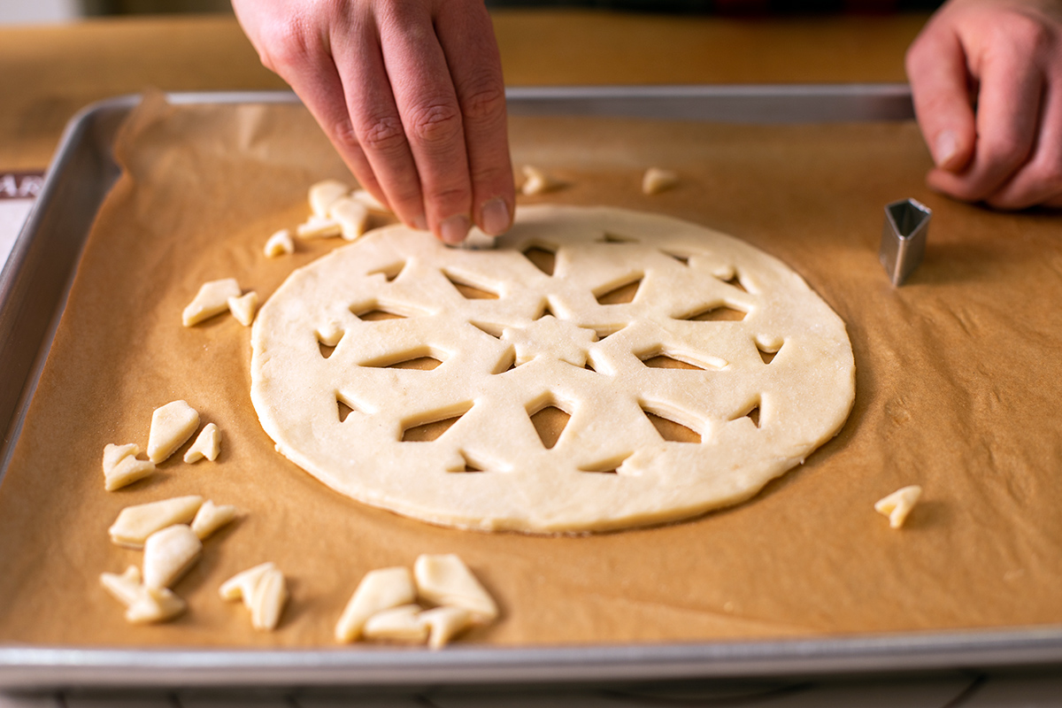 Rolled out pie dough with shapes cut out in a stencil pattern