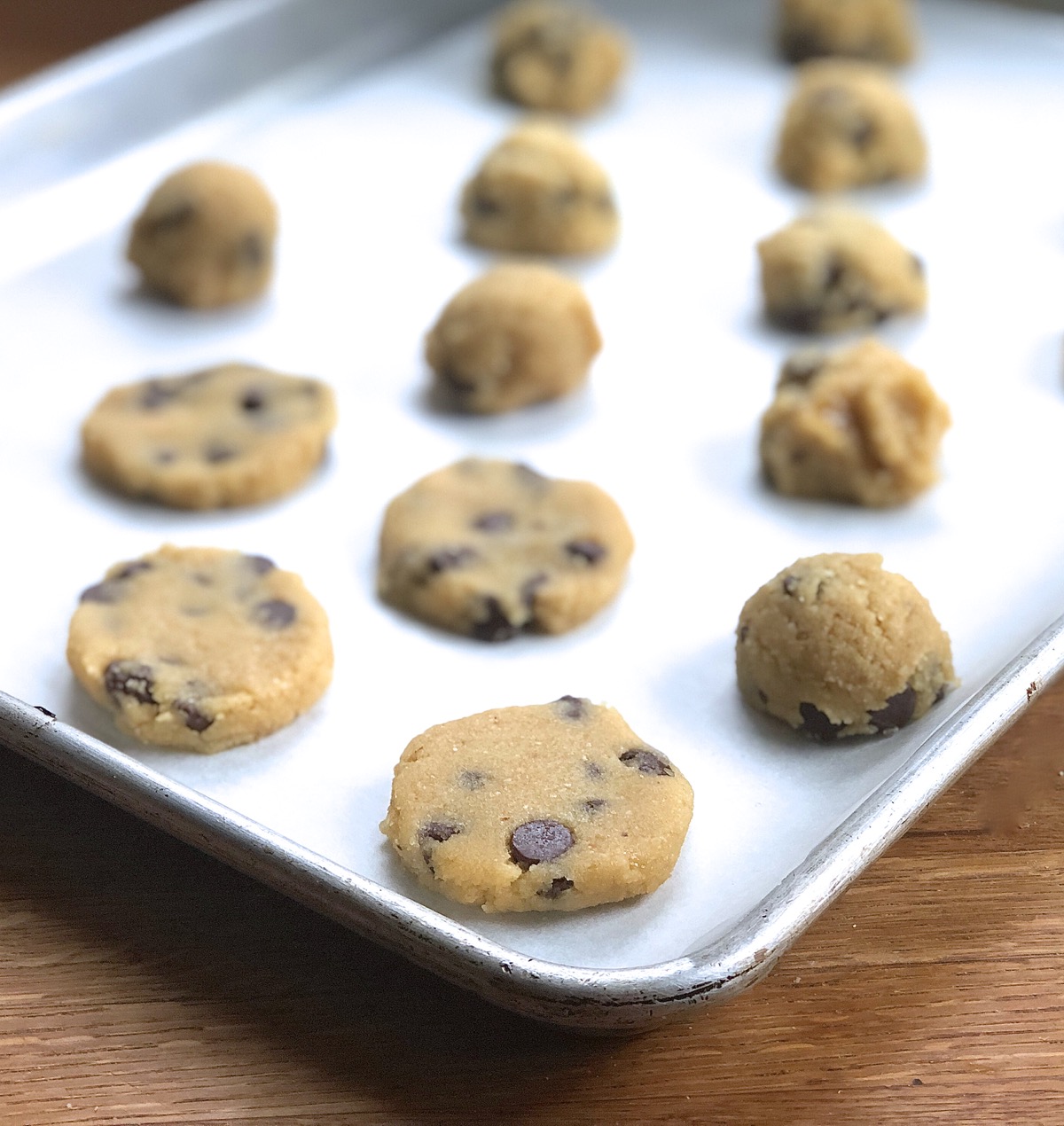 Dough for Gluten-Free Almond Flour Chocolate Chip Cookies scooped in balls onto a baking sheet and gently flattened.