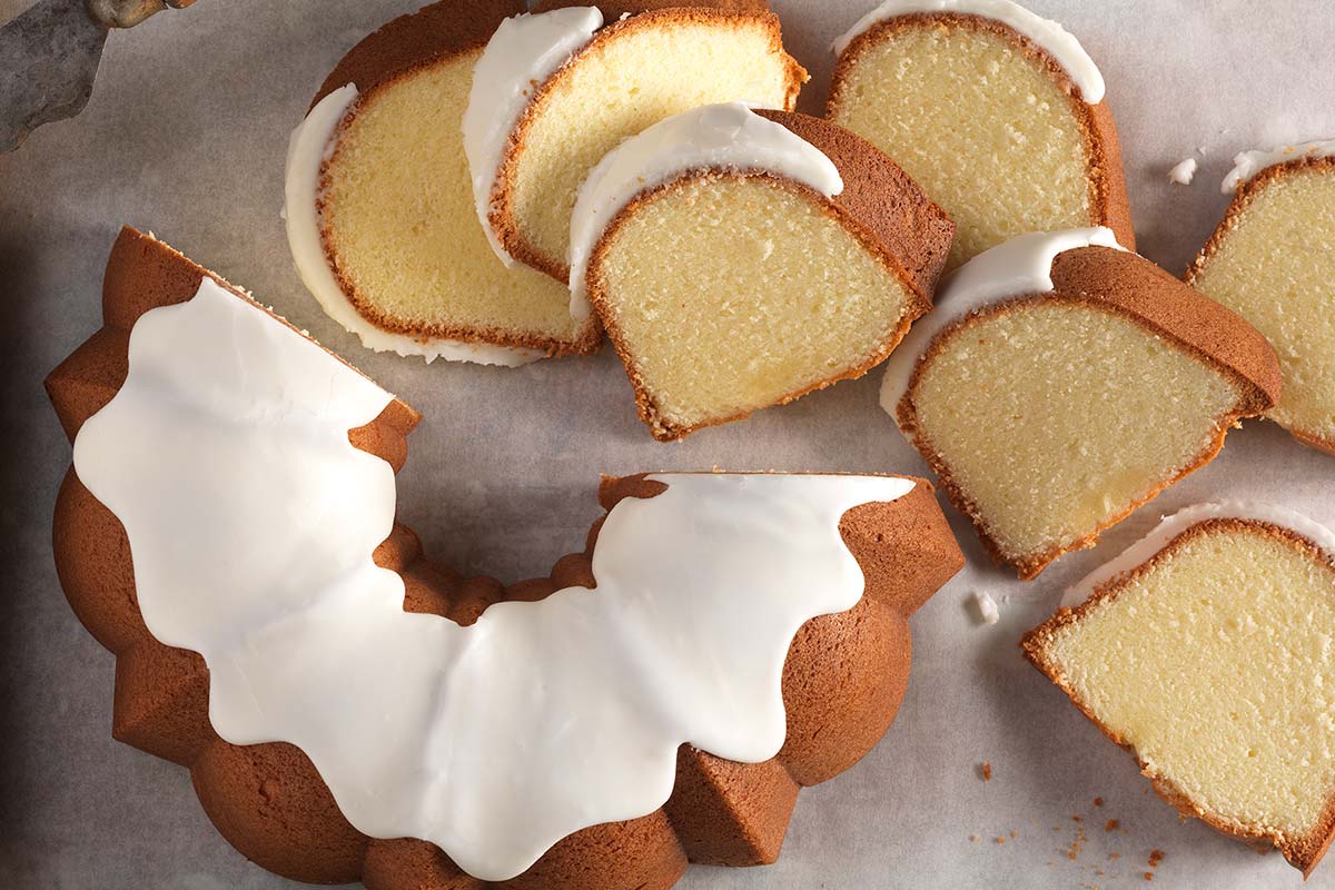 A Gluten-Free Almond Bundt Cake covered with glaze and a few slices taken out of it