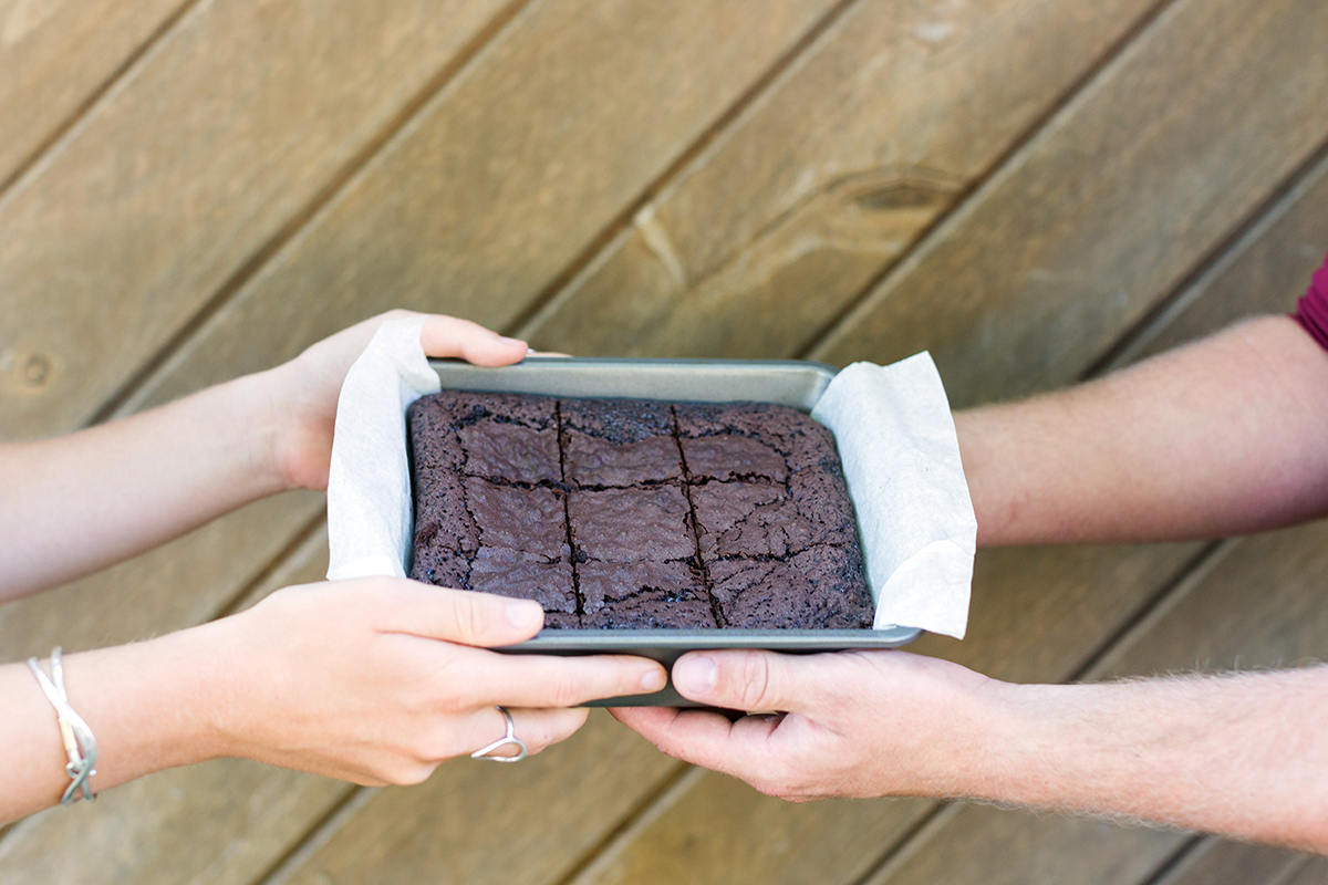 A baker giving a pan of gluten-free brownies to a friend